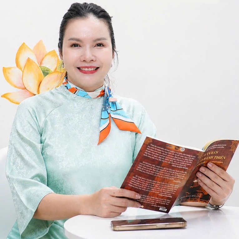 Moon Nguyễn mỉm cười, ngồi đọc sách bên bức tường vẽ hoa sen