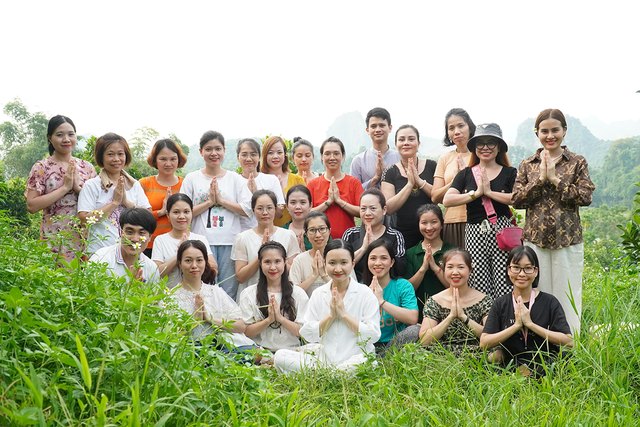 Học viên Level 1 chắp tay chụp ảnh chung trên đồi cỏ giữa vùng núi