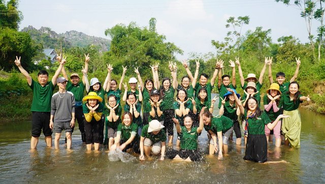 Học viên Level 1 lội suối, giơ tay cười trong một buổi ngoài trời