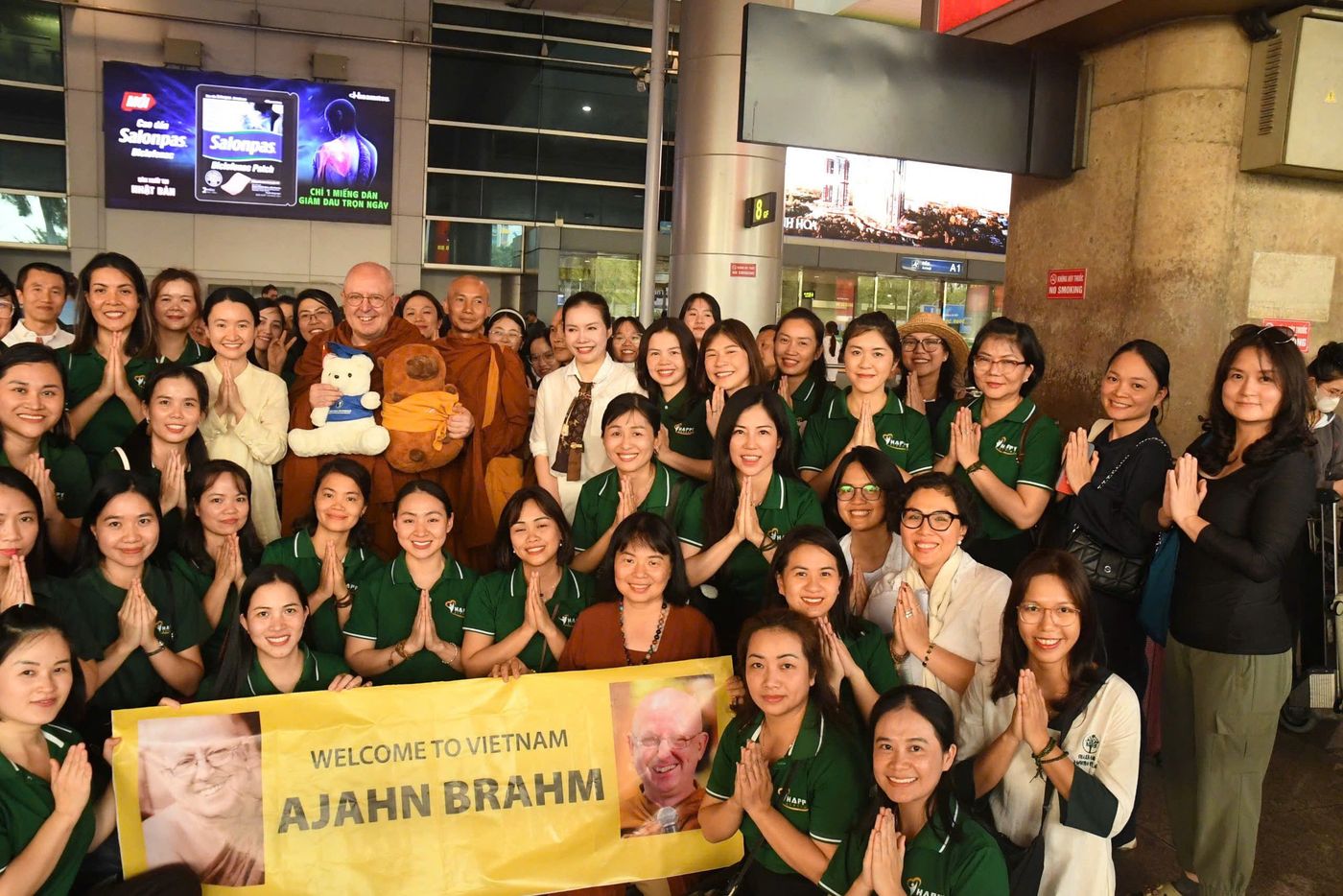 Đội ngũ Happy Academy chắp tay đón thiền sư Ajahn Brahm tại sân bay, cầm băng-rôn Welcome to Vietnam